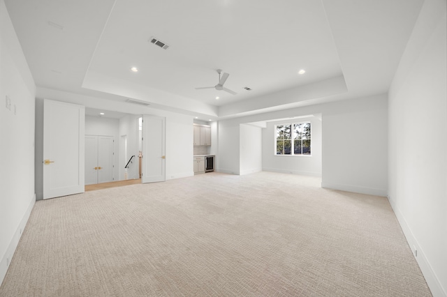 unfurnished living room featuring baseboards, visible vents, a raised ceiling, and a ceiling fan