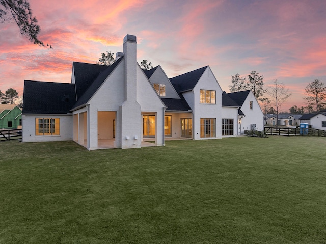 back of property with a chimney, fence, and a yard