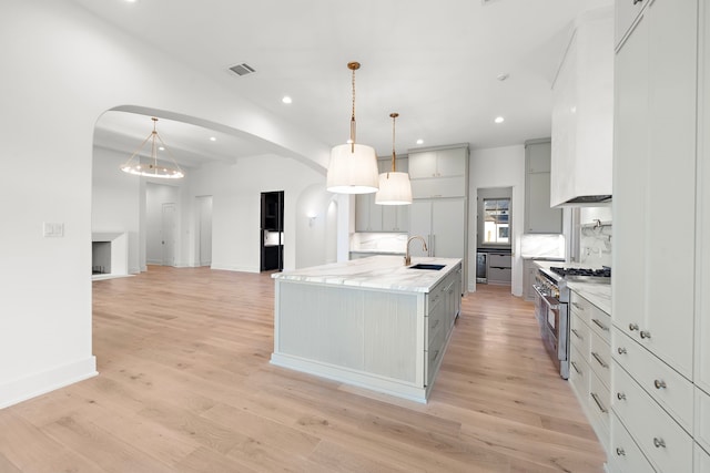 kitchen with stainless steel range, a sink, visible vents, and gray cabinetry