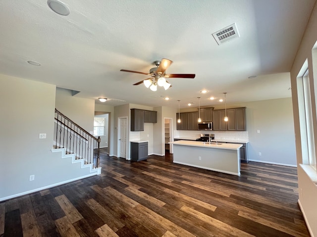 kitchen with dark hardwood / wood-style floors, hanging light fixtures, a center island with sink, and ceiling fan