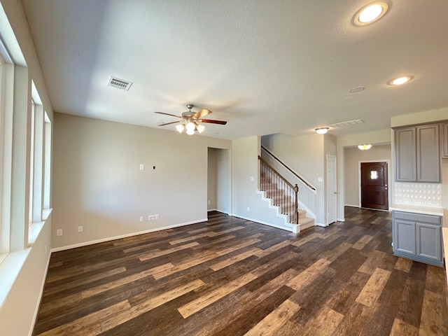 unfurnished living room featuring dark wood-type flooring and ceiling fan