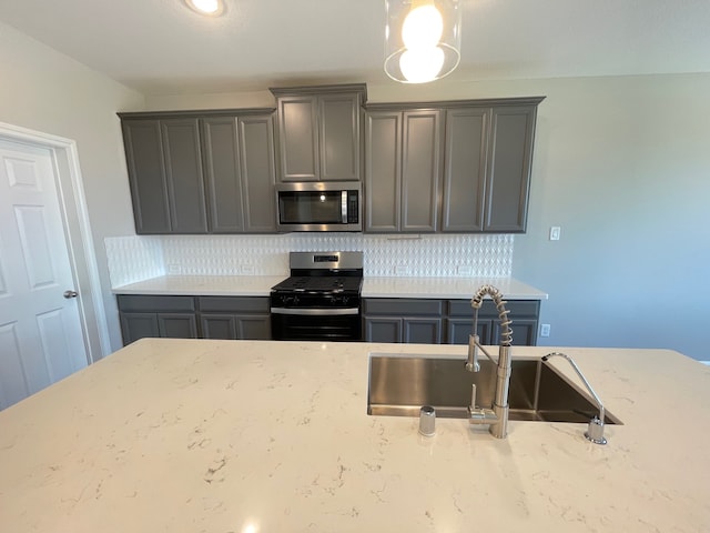 kitchen with backsplash, light stone counters, appliances with stainless steel finishes, and sink