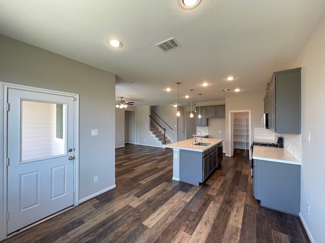 kitchen with a center island with sink, sink, hanging light fixtures, dark hardwood / wood-style floors, and ceiling fan