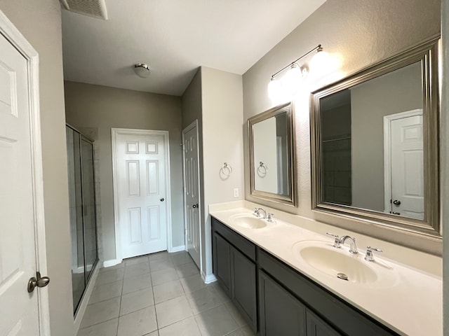 bathroom with a shower with shower door, tile patterned floors, and dual bowl vanity