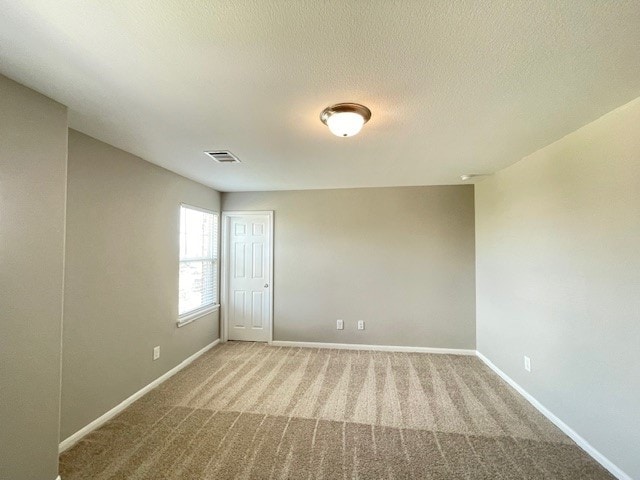 carpeted empty room with a textured ceiling