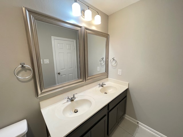 bathroom with dual vanity, tile patterned flooring, and toilet