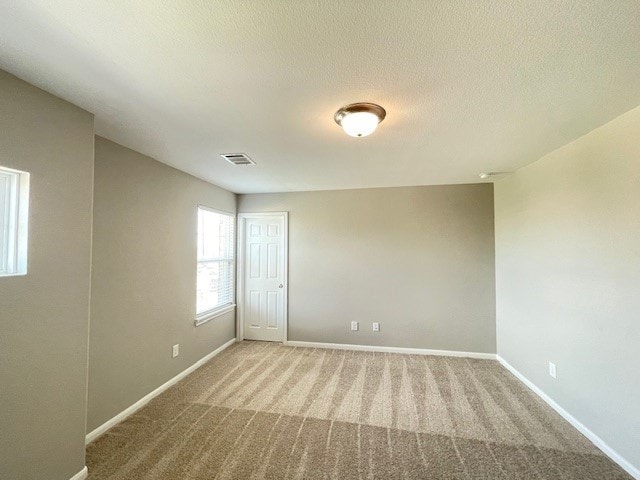 empty room with a textured ceiling and carpet flooring