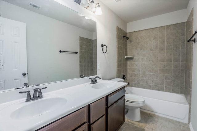 full bathroom with tile patterned flooring, tiled shower / bath combo, toilet, and vanity