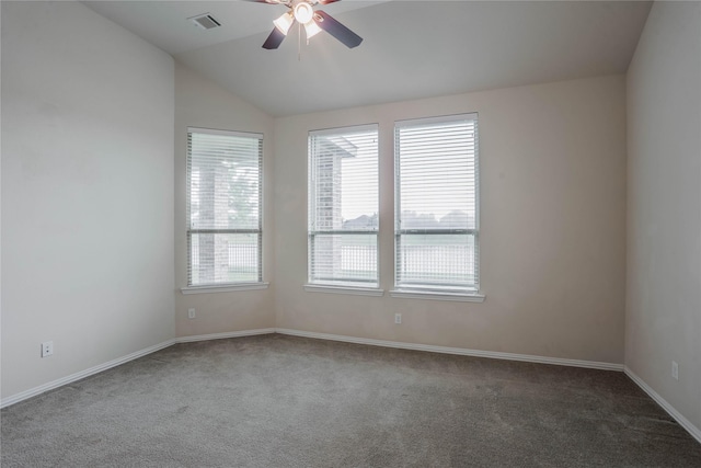 spare room featuring vaulted ceiling, dark carpet, plenty of natural light, and ceiling fan