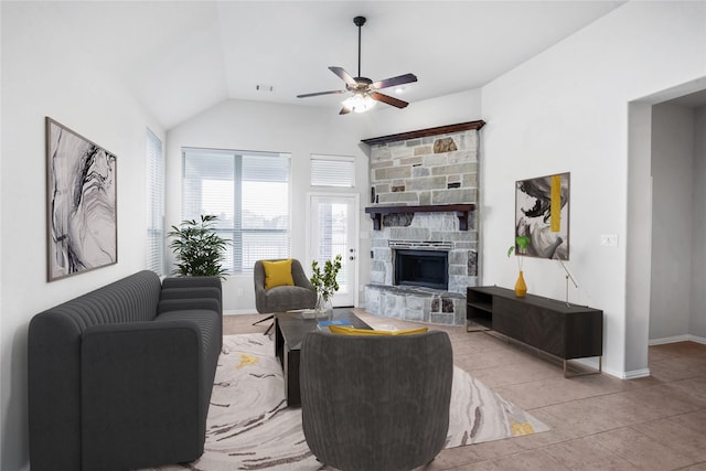 living room featuring a stone fireplace, ceiling fan, light tile patterned floors, and lofted ceiling