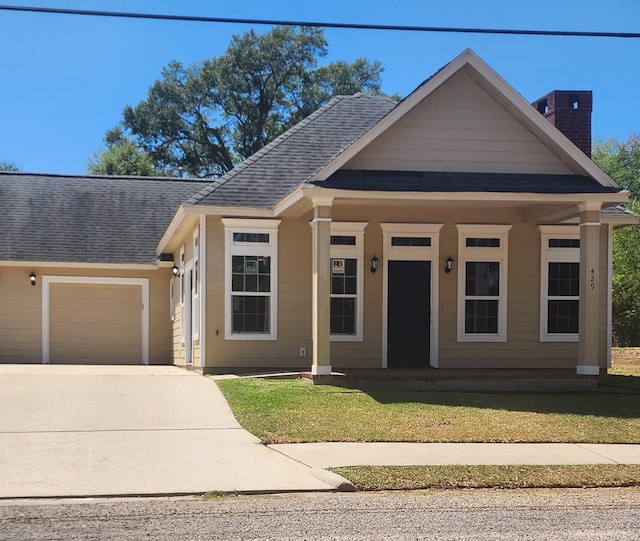 view of front of home with a garage, a front lawn, and a porch