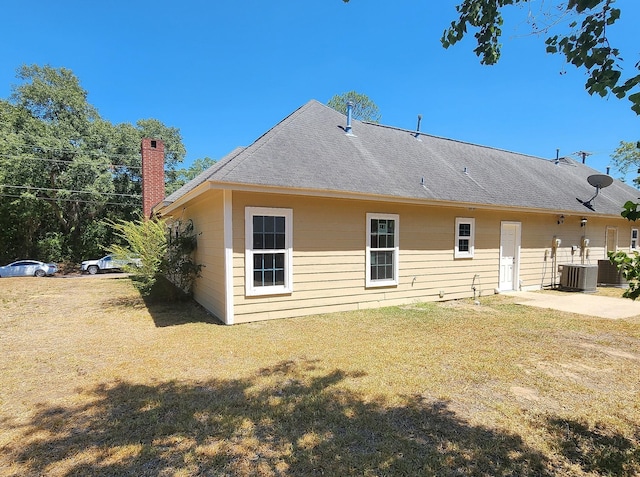 rear view of house with a patio, cooling unit, and a lawn