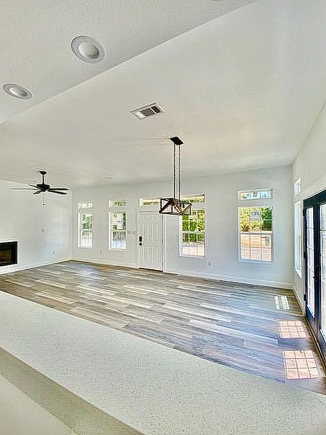 unfurnished living room with ceiling fan and wood-type flooring