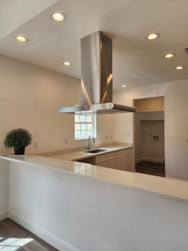 kitchen featuring kitchen peninsula, island range hood, dark wood-type flooring, and sink