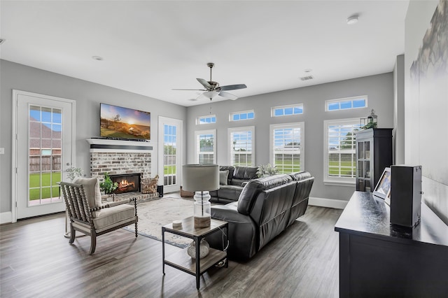 living room with ceiling fan, wood-type flooring, and a brick fireplace