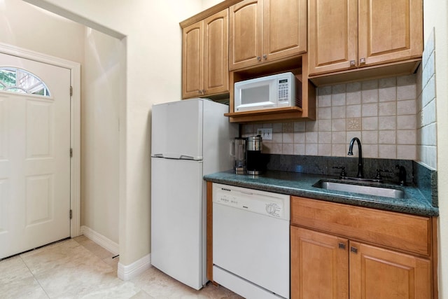 kitchen featuring white appliances, backsplash, dark stone counters, sink, and light tile patterned floors