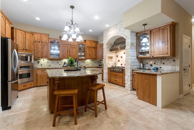 kitchen featuring appliances with stainless steel finishes, a center island, tasteful backsplash, and an inviting chandelier