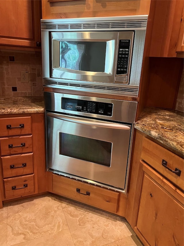 kitchen featuring dark stone countertops, backsplash, and appliances with stainless steel finishes