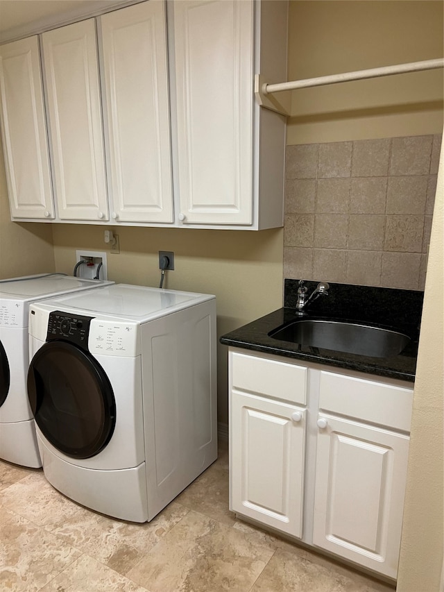 clothes washing area with washing machine and dryer, sink, and cabinets