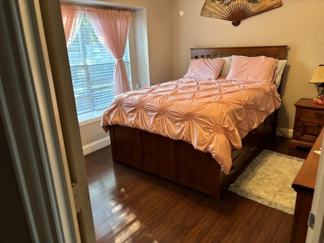 bedroom with multiple windows and dark hardwood / wood-style flooring