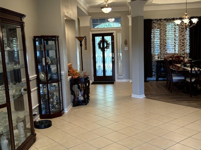 foyer entrance featuring ornamental molding, light parquet floors, decorative columns, and a chandelier