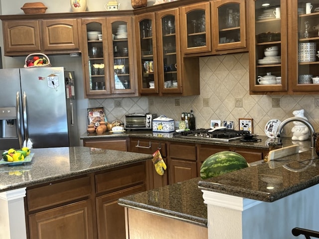 kitchen featuring appliances with stainless steel finishes, dark stone countertops, and decorative backsplash