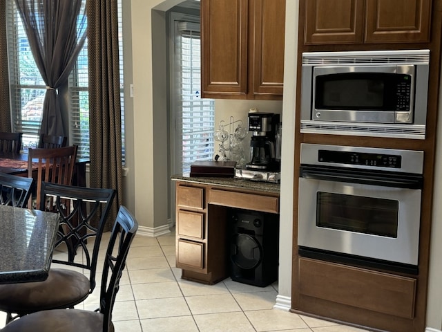 kitchen featuring stainless steel appliances, dark stone countertops, and light tile patterned floors