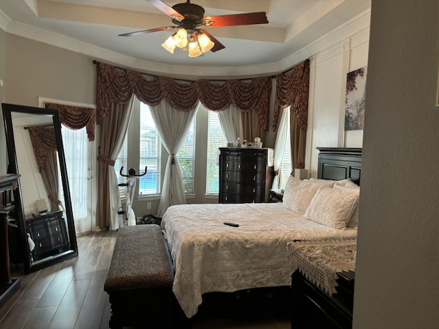 bedroom with hardwood / wood-style flooring, a raised ceiling, crown molding, and ceiling fan