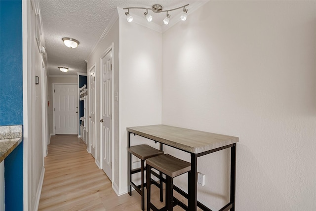 hall featuring a textured ceiling, light hardwood / wood-style flooring, and ornamental molding