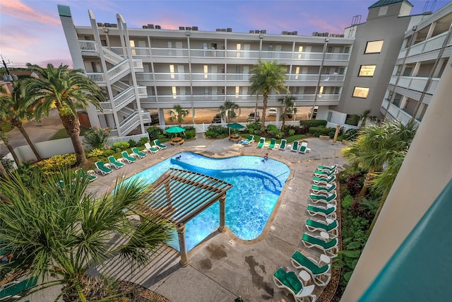 pool at dusk featuring a patio