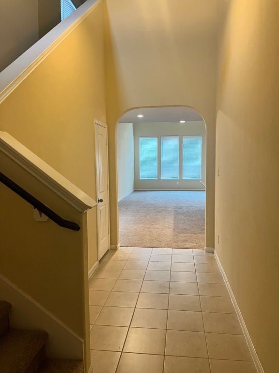 hall featuring light colored carpet and a high ceiling