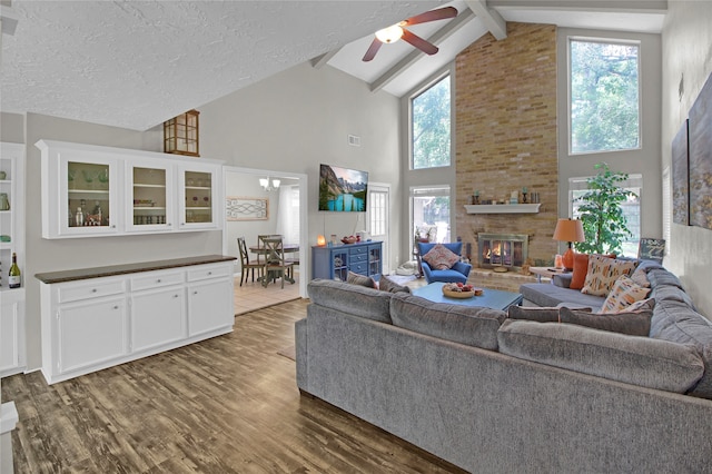 living room with beamed ceiling, hardwood / wood-style floors, a fireplace, high vaulted ceiling, and ceiling fan