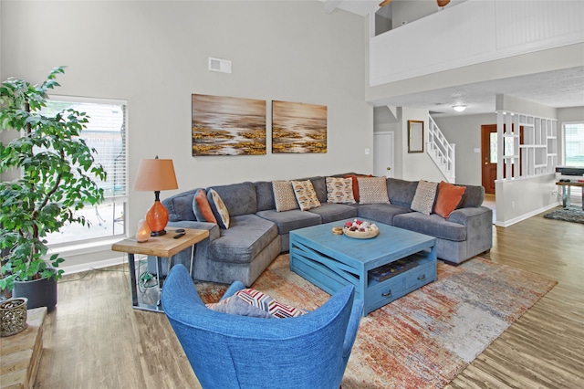 living room with hardwood / wood-style floors, plenty of natural light, and a towering ceiling