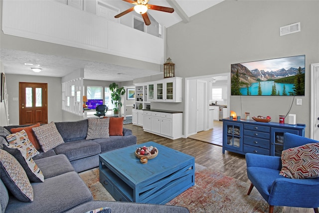 tiled living room with ceiling fan and a towering ceiling