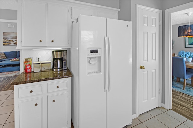 kitchen featuring dark stone counters, white cabinets, decorative backsplash, light wood-type flooring, and white fridge with ice dispenser