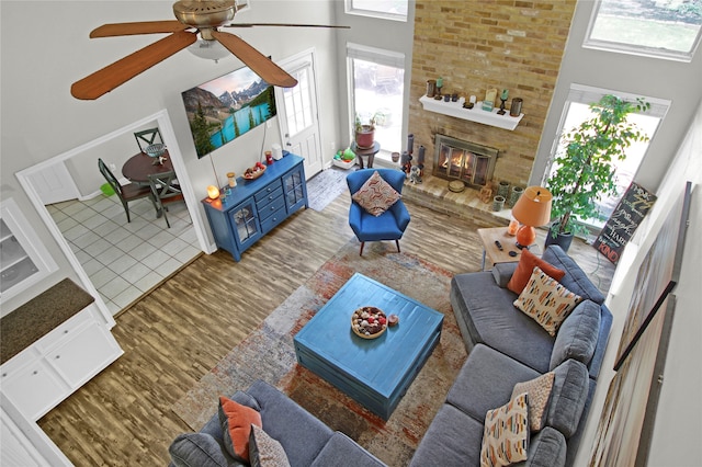 living room featuring wood-type flooring, brick wall, a towering ceiling, and ceiling fan