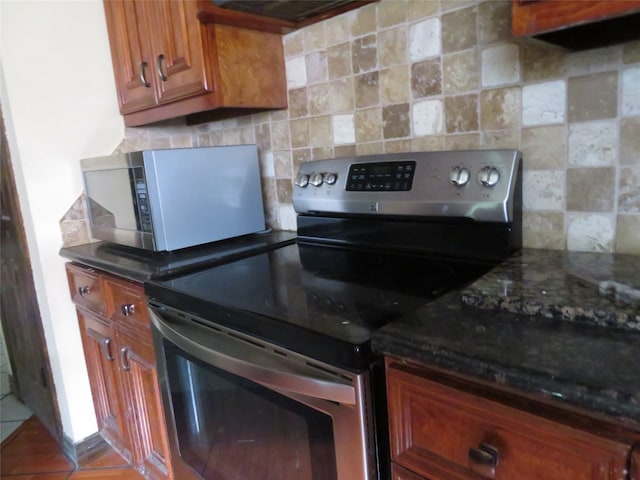 kitchen with appliances with stainless steel finishes, backsplash, and dark stone countertops