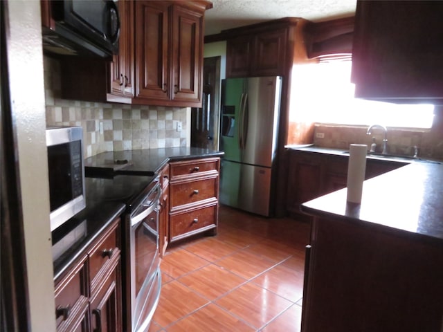 kitchen with a textured ceiling, stainless steel appliances, backsplash, and light tile patterned floors