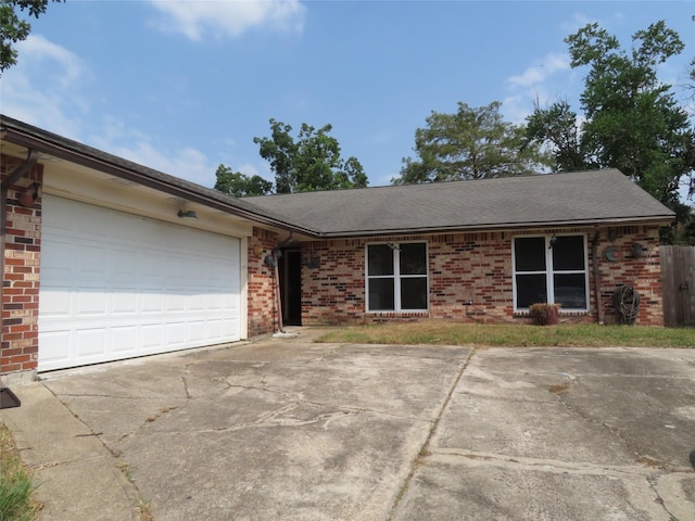 single story home with brick siding, an attached garage, a shingled roof, and concrete driveway
