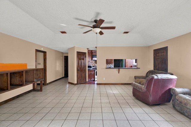 living room featuring a textured ceiling, light tile patterned floors, and ceiling fan