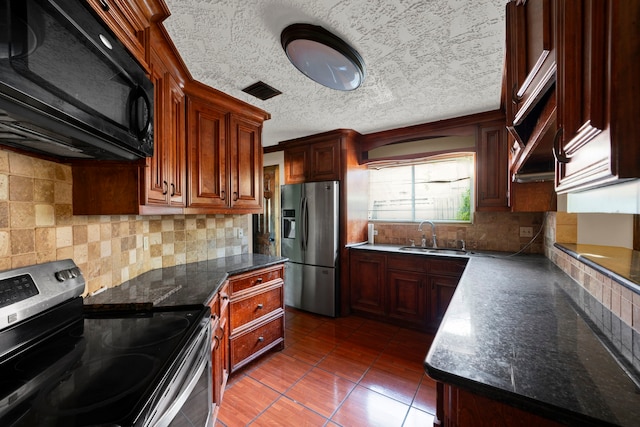 kitchen with decorative backsplash, appliances with stainless steel finishes, a textured ceiling, dark tile patterned floors, and sink