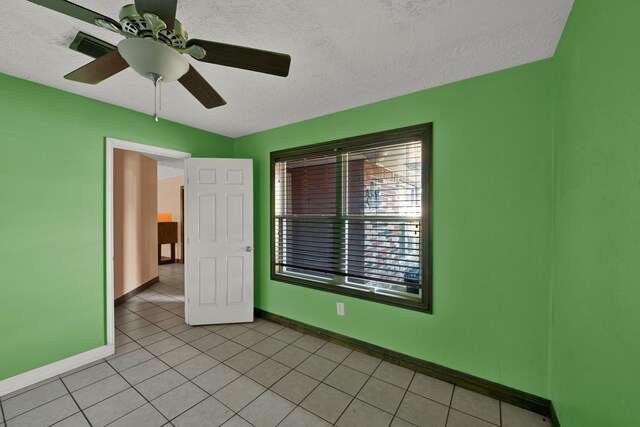 spare room with a textured ceiling, light tile patterned floors, and ceiling fan