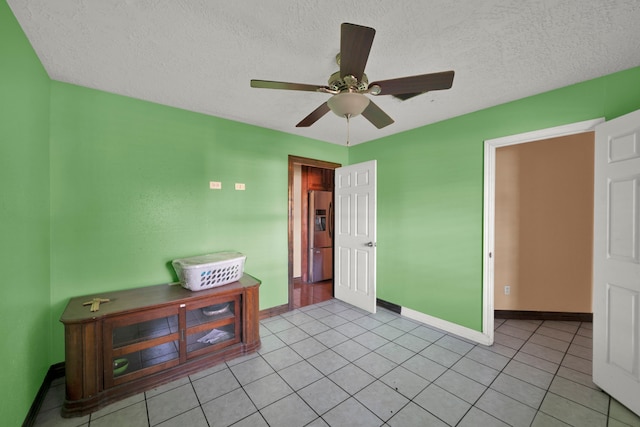 tiled bedroom with stainless steel refrigerator with ice dispenser, a textured ceiling, and ceiling fan