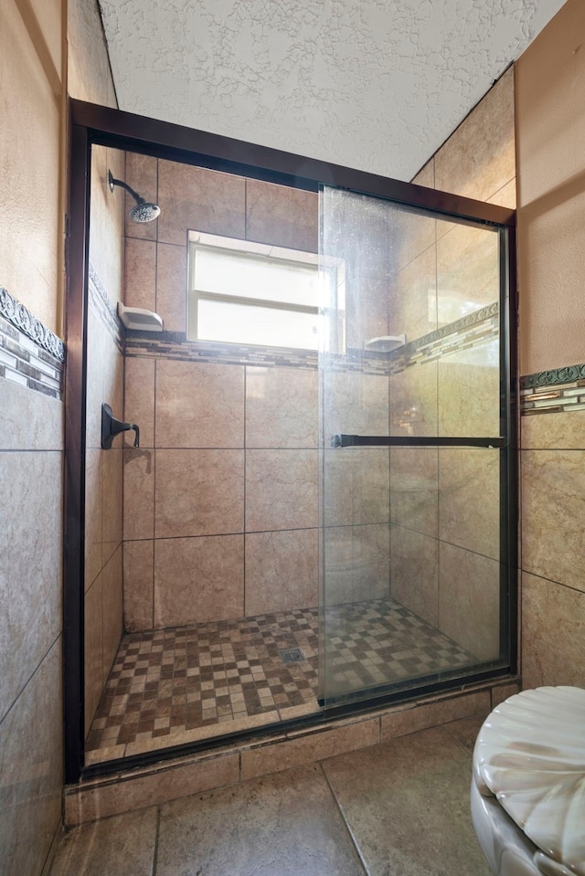 bathroom with toilet, walk in shower, and a textured ceiling