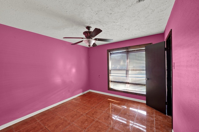 tiled empty room with ceiling fan and a textured ceiling