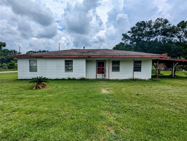 rear view of property with a carport and a lawn