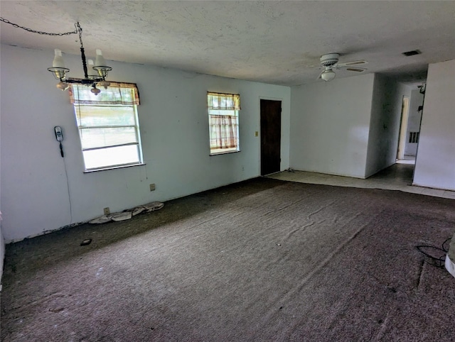 spare room with carpet, a textured ceiling, and ceiling fan with notable chandelier