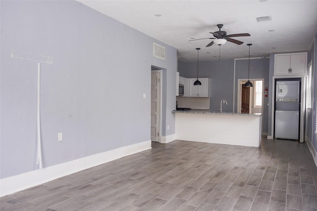 unfurnished living room featuring baseboards, a ceiling fan, wood finished floors, and visible vents