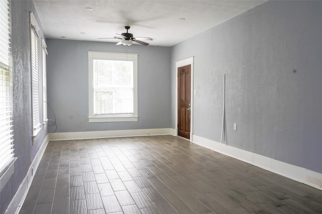 spare room with baseboards, a ceiling fan, and dark wood finished floors