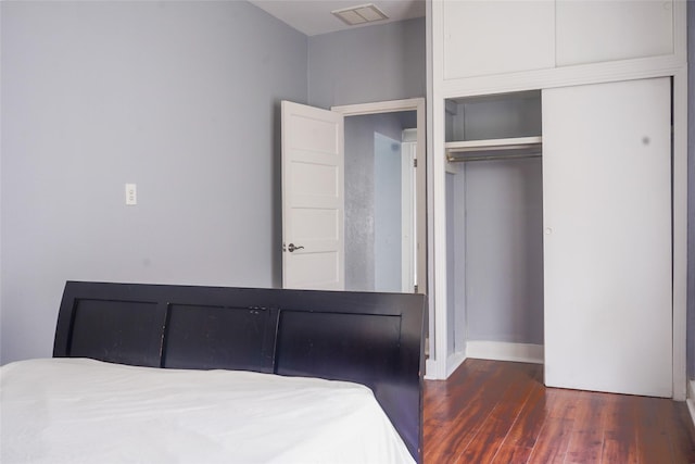 unfurnished bedroom featuring visible vents, baseboards, wood finished floors, and a closet